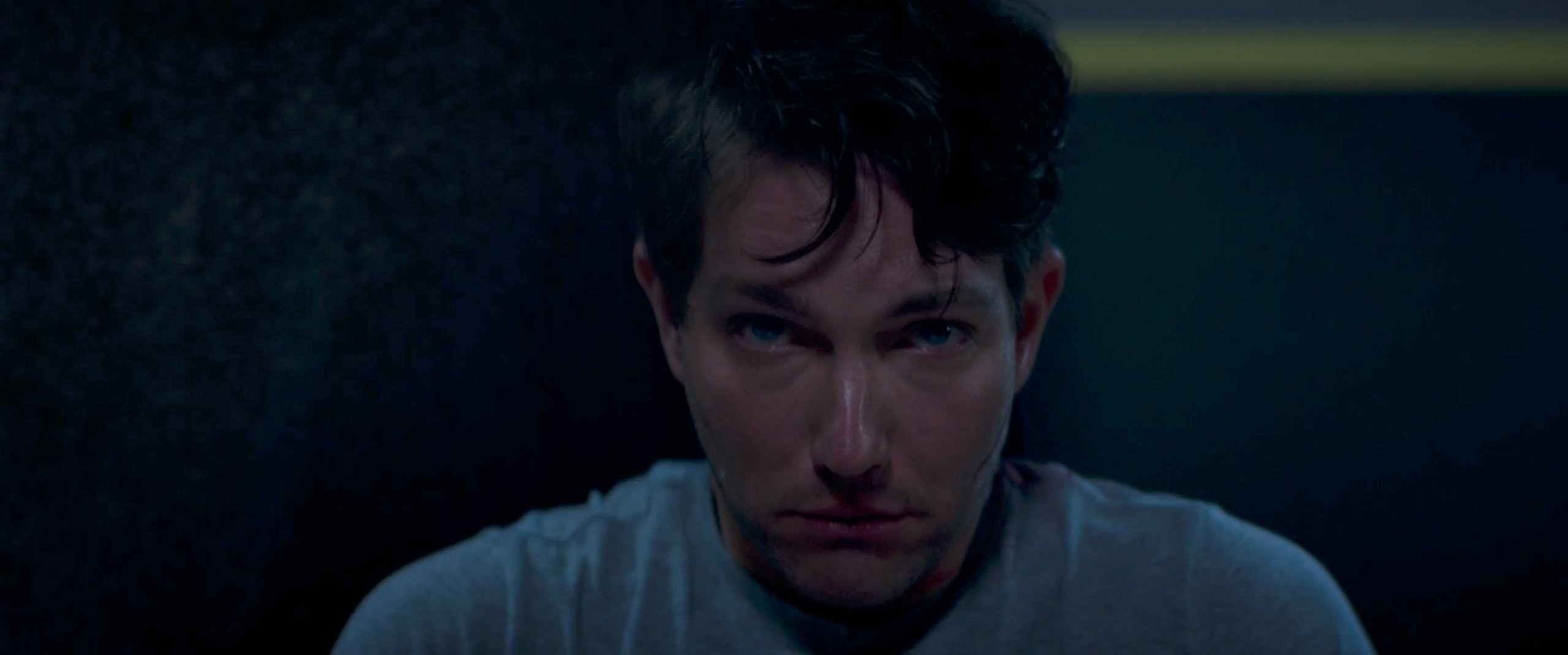 Close-up in shadow. Damp hair, eyes locked down.