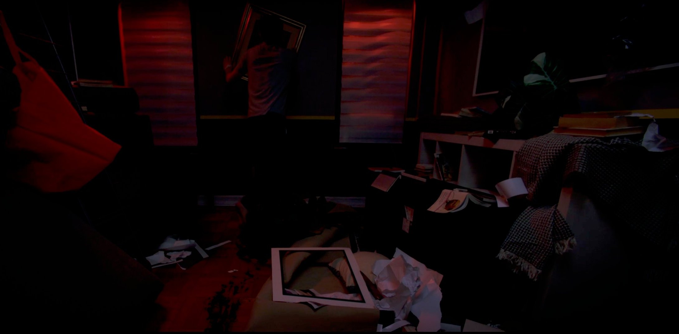 Ransacked room. A figure at the wall, red light behind.