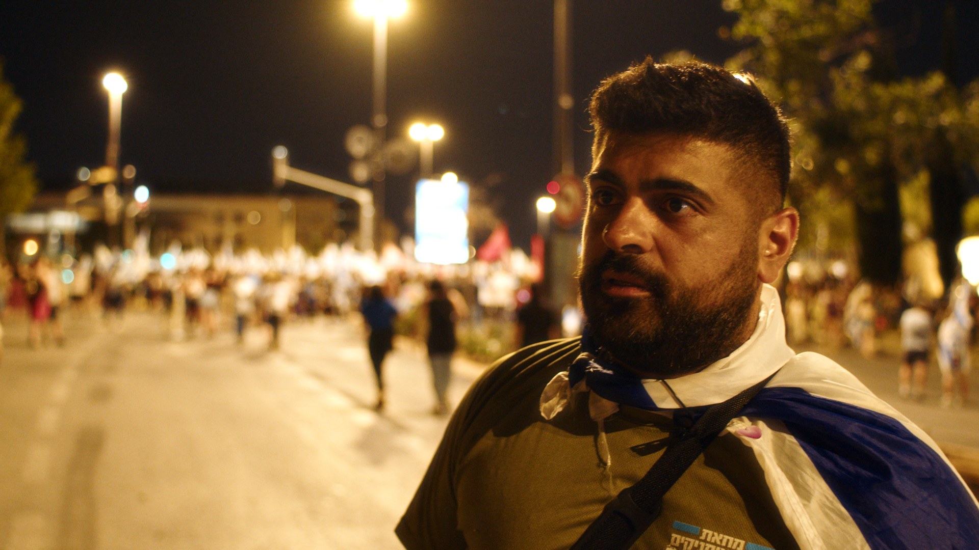 Demonstrator wrapped in the flag. Streetlight.